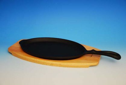 Żeliwna patelnia z drewnianą deską do serwowania fajity.